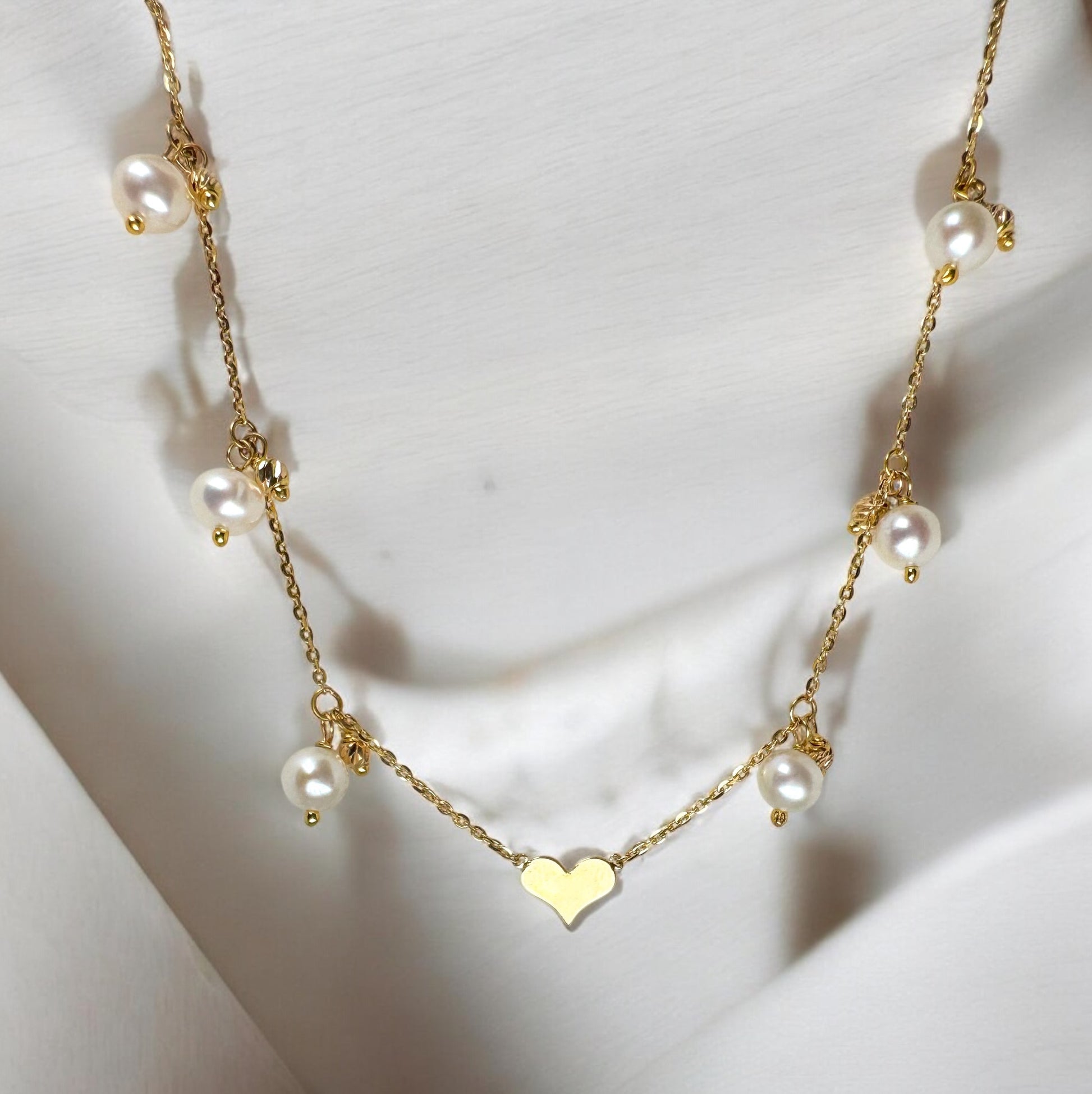 Elegant 18K yellow gold pearl necklace featuring a delicate heart-shaped pendant and multiple lustrous pearls on a fine gold chain. valentine's day gifts for her,
diamond heart necklace,
valentines gift for her,
valentines gifts for men,
valentine gift for wife, valentines day gifts for wife, pearl necklace,
18k yellow gold,
heart necklace,
christmas gift,
christmas stockings,
christmas gift ideas,
personalized Christmas ornaments, Valentin's day gift for women